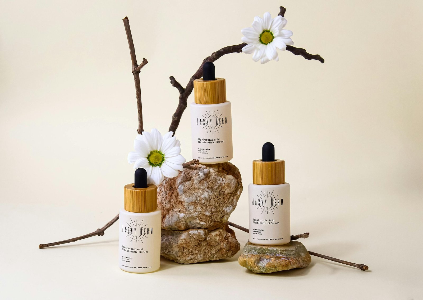 Organic hyaluronic acid serum bottles with floral and stone arrangement on neutral background.